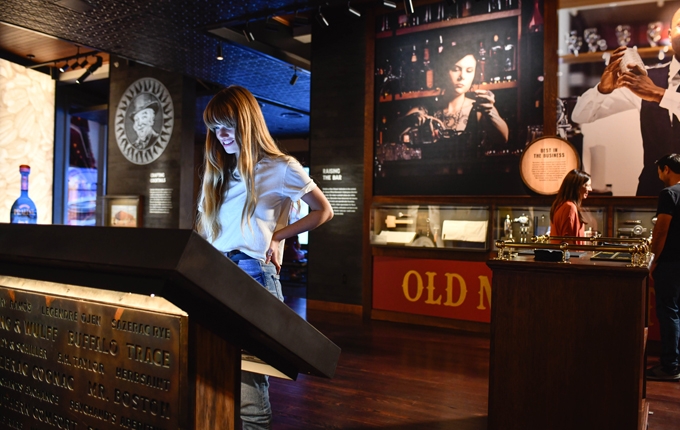 a woman engaging with an interactive exhibit at the Sazerac House