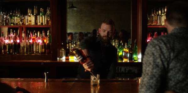 Bartender pours drink in dimly lit bar